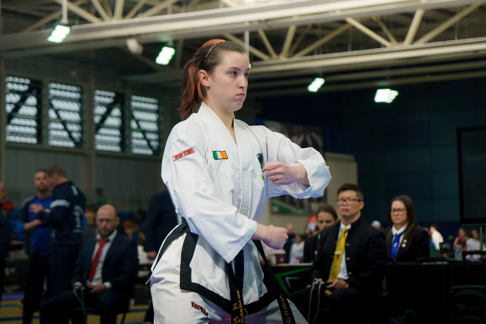 Black belt athlete performing a high side kick in a pattern