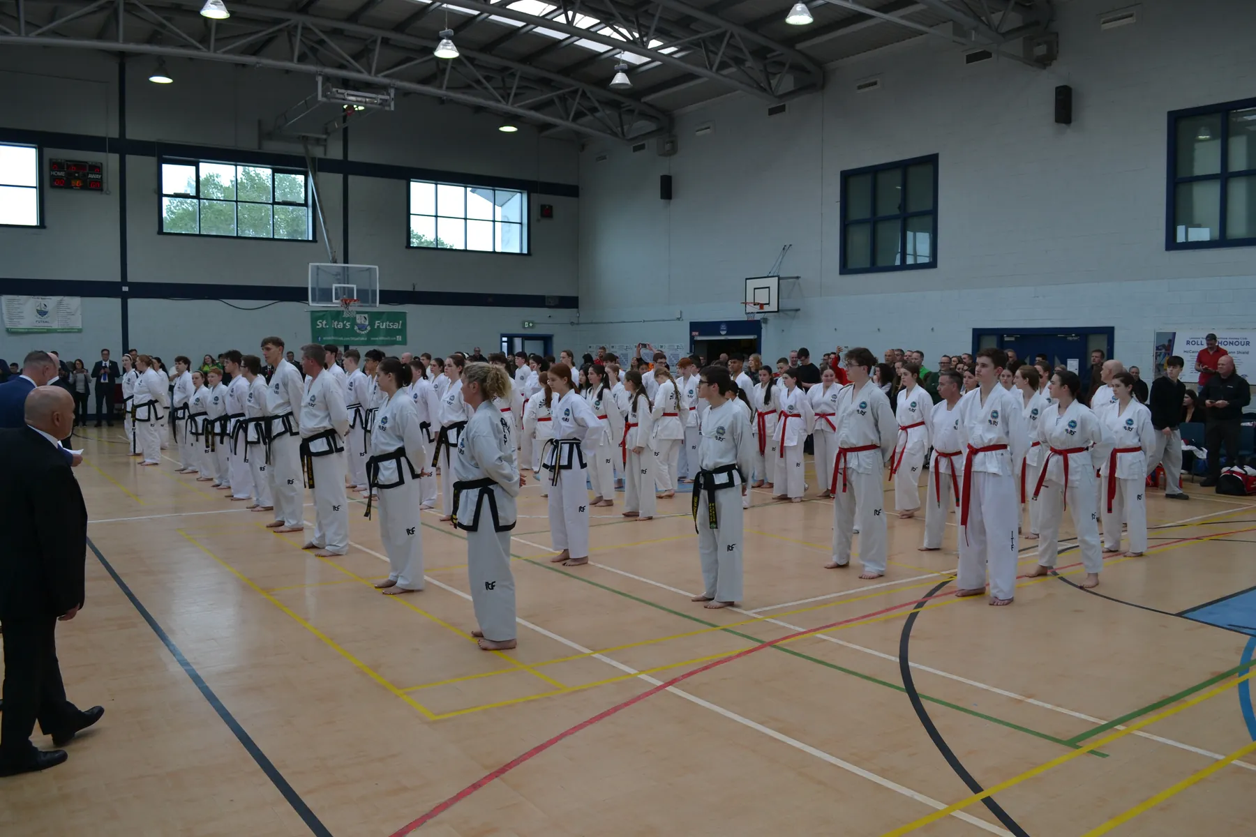 Rows of students lined up across a sports hall for a grading